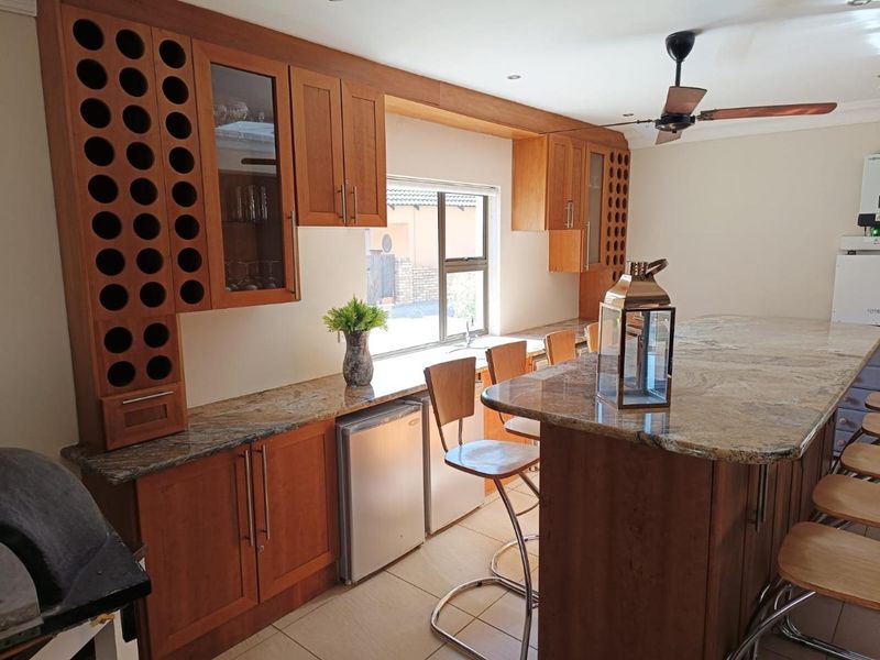 A functional kitchen featuring warm wooden cabinetry, granite countertops, a built-in wine rack, and a central island with breakfast bar seating.