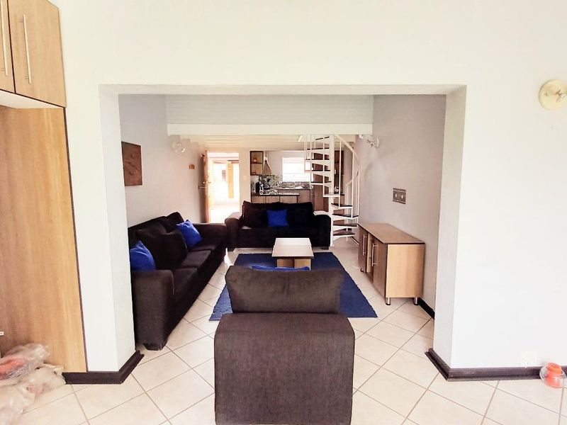 Open plan living area featuring tiled flooring and a spiral staircase leading to an upper level.