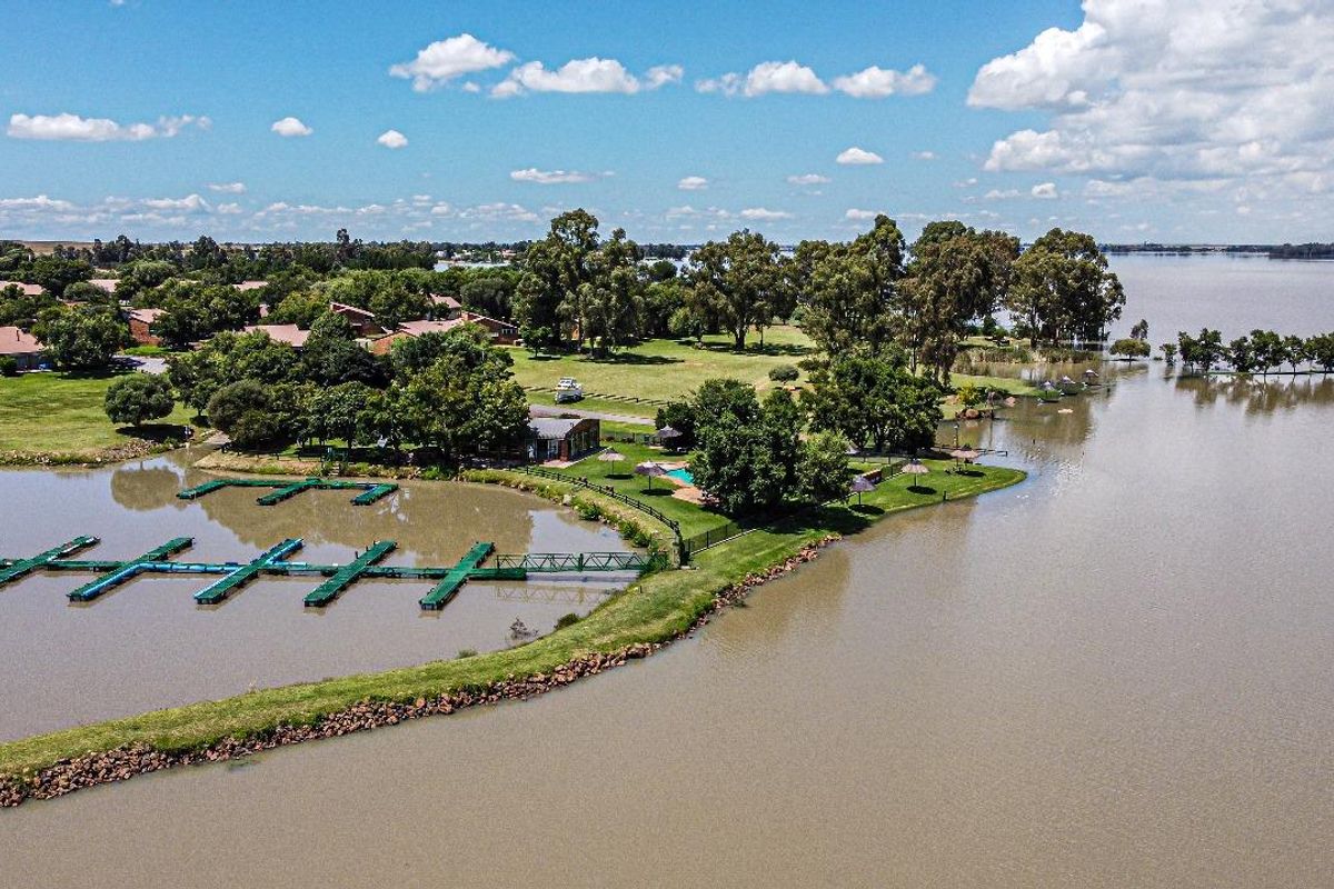 Aerial view of the waterfront estate featuring a private boat jetty, swimming pool, and expansive landscaped grounds along the shoreline.