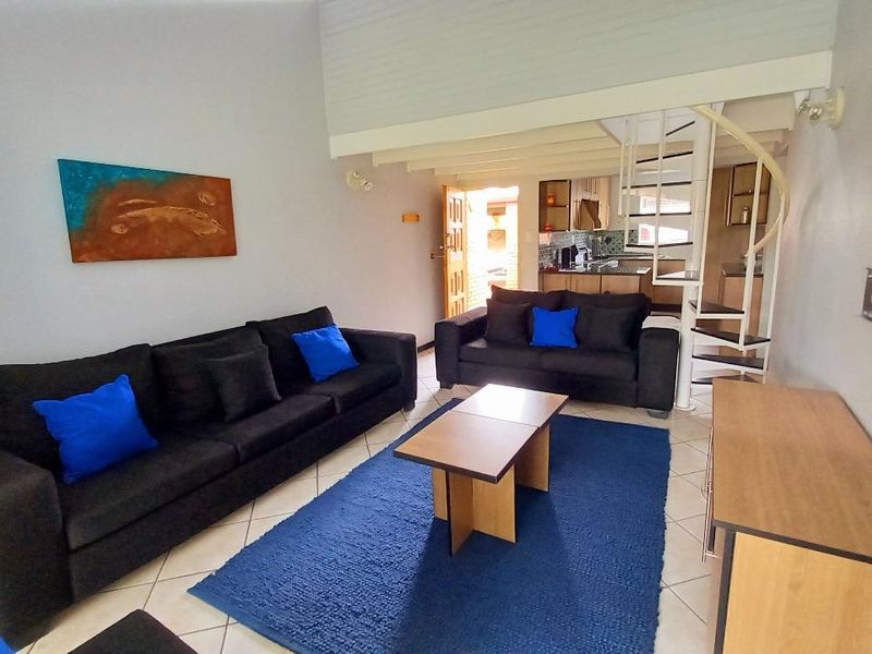 Open-plan living area featuring tiled flooring, a spiral staircase leading to an upper level, and an integrated kitchen space.