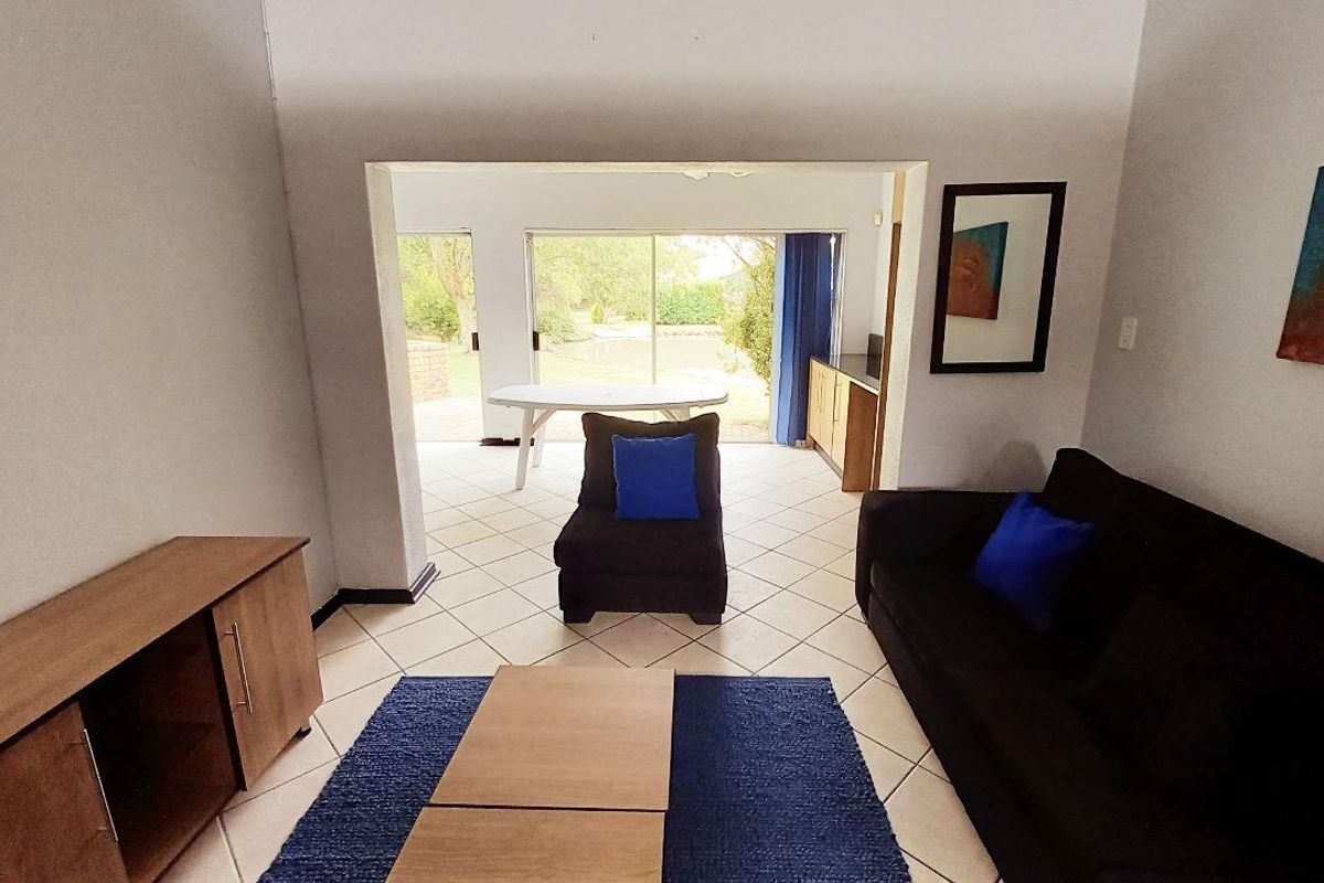 A living room featuring tiled flooring and sliding glass doors that provide direct access to an outdoor patio area.