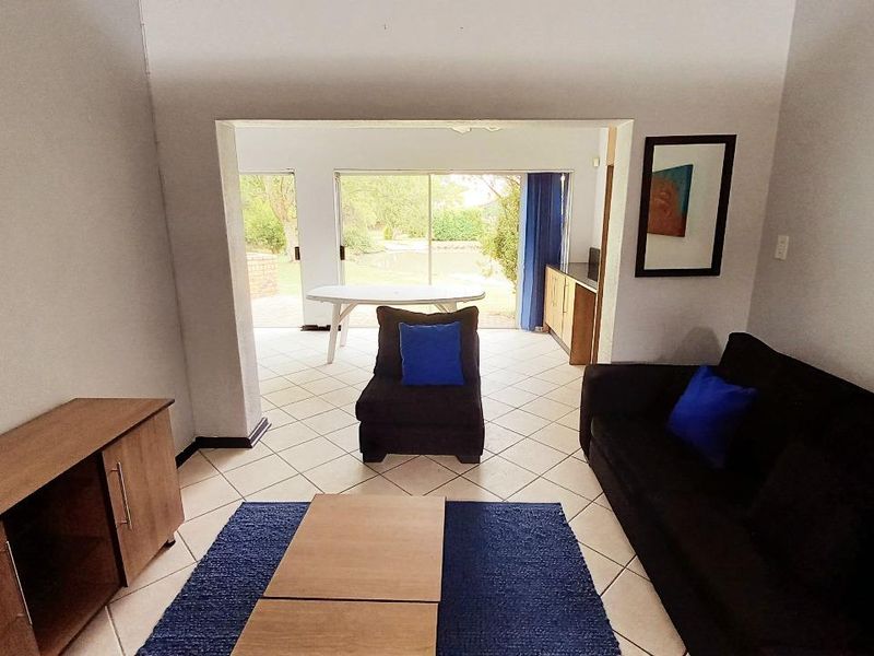A living room featuring tiled flooring and sliding glass doors that provide direct access to an outdoor patio area.