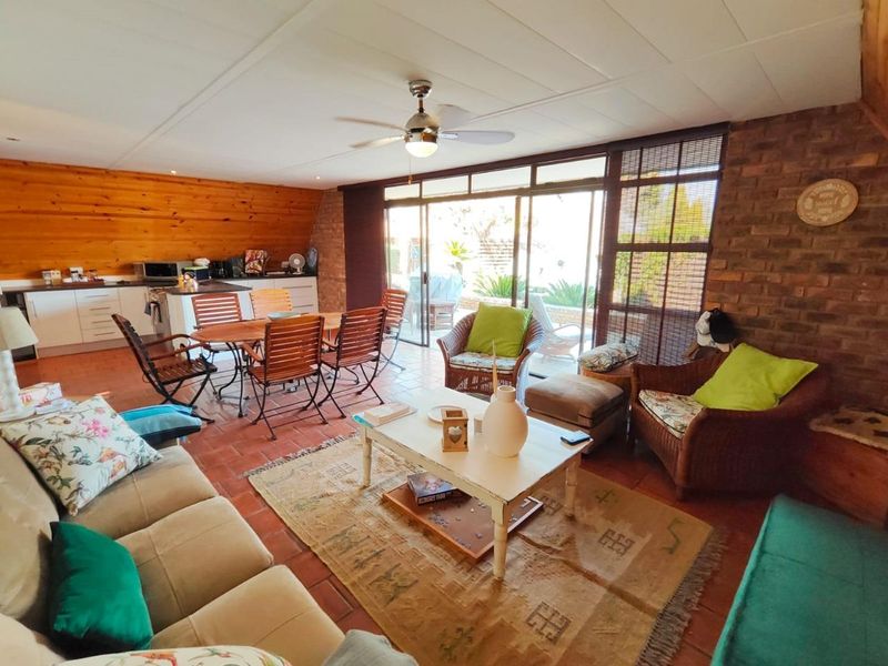 Spacious open-plan living and dining area featuring exposed brickwork, timber paneling, tiled floors, and large sliding doors providing access to the outdoor space.