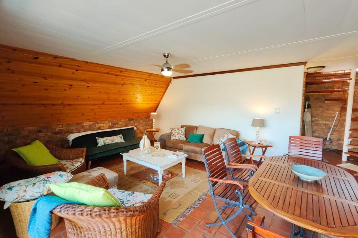 Spacious living area featuring a combination of exposed brick and timber paneling, complemented by traditional terracotta floor tiles and a ceiling fan.