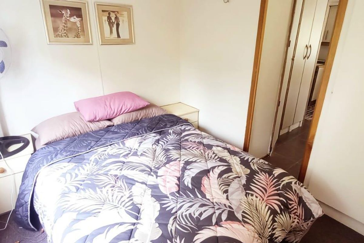 A compact bedroom featuring built-in storage cupboards and neutral wall finishes, providing a functional sleeping space.