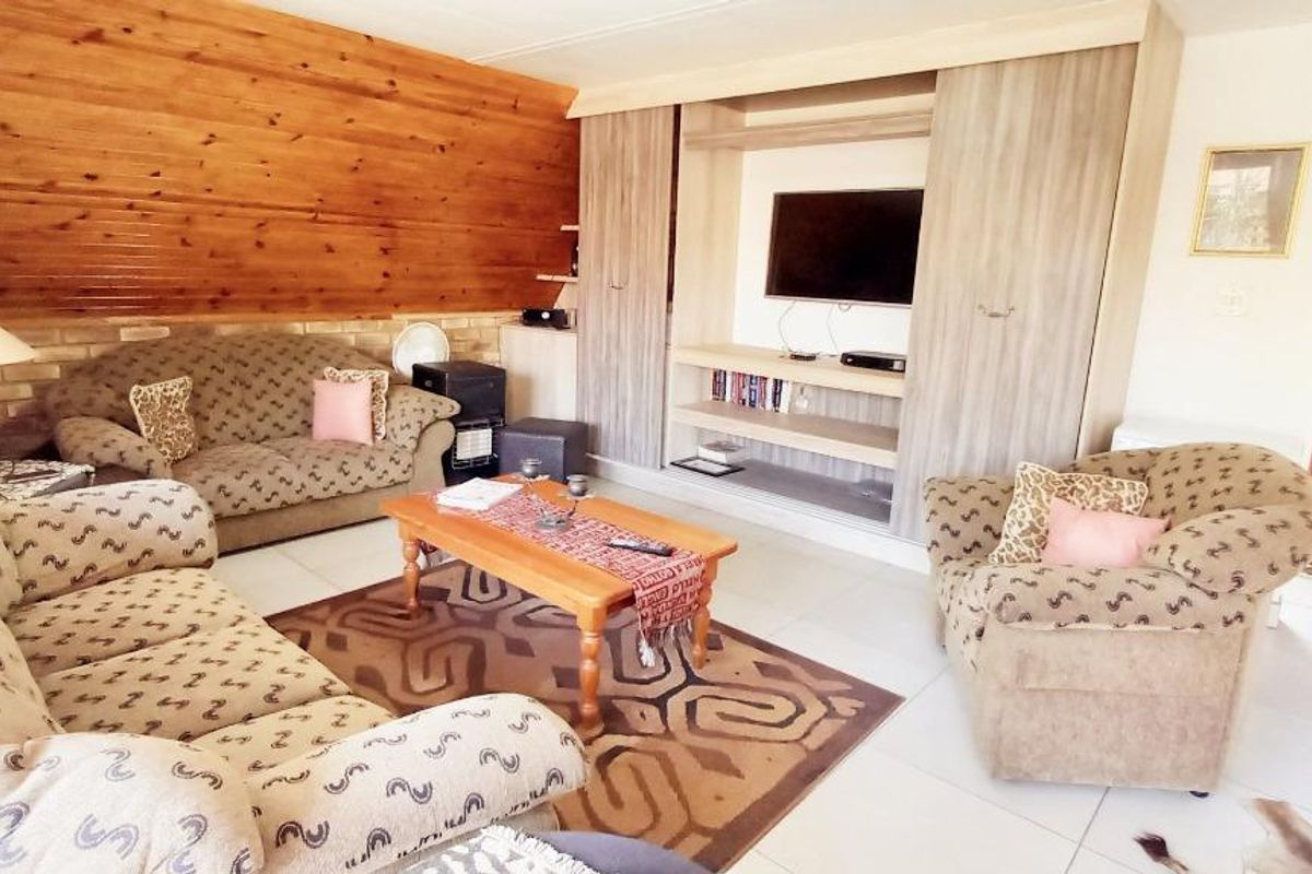 A living room featuring a wood-paneled feature wall, built-in cabinetry, and tiled flooring, offering a cozy and functional space.