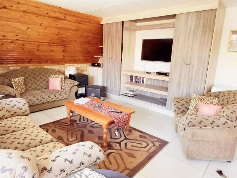 A living room featuring a wood-paneled feature wall, built-in cabinetry, and tiled flooring, offering a cozy and functional space.