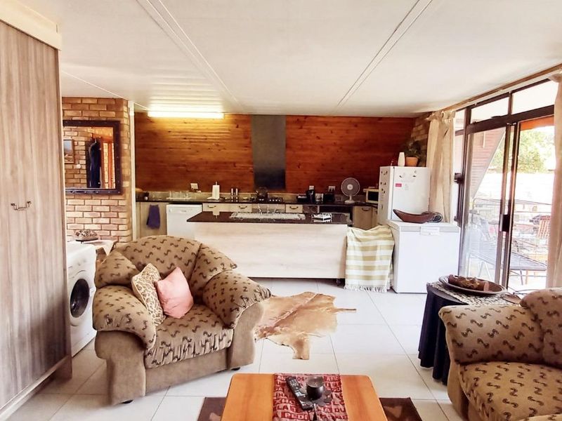 Open-plan living and kitchen area featuring wood paneling, exposed brick accents, a central kitchen island, and sliding glass doors leading to the outdoors.