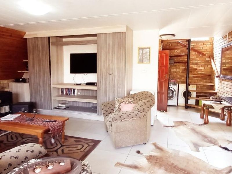 Open-plan living area featuring timber wall paneling, exposed brickwork, a spiral staircase, and a kitchen island with integrated cabinetry.