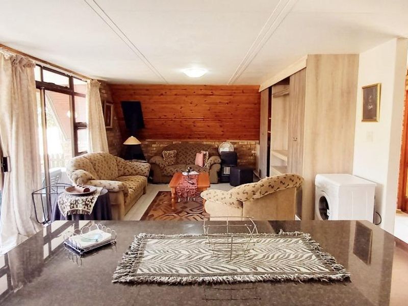 Open-plan living area featuring timber wall paneling, exposed brick accents, and a stone-topped kitchen island with direct access to the patio.