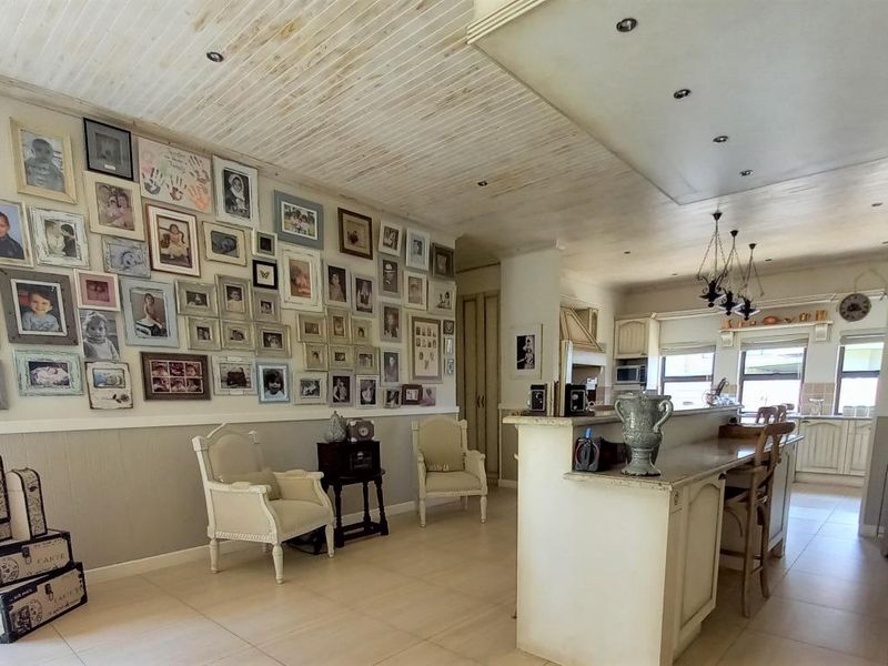 Open plan living and kitchen area featuring a breakfast bar, tiled flooring, wainscoting, and a distinctive tongue and groove ceiling.