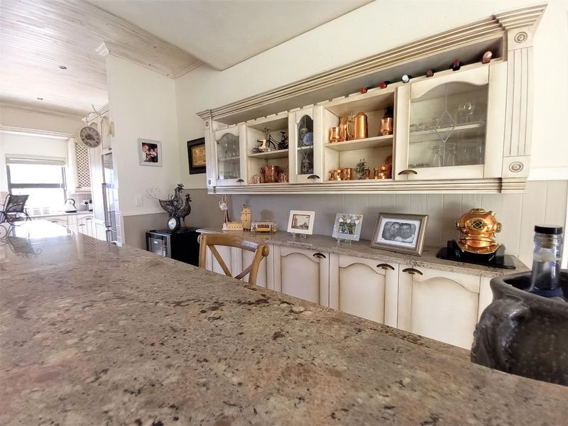 A well-maintained kitchen featuring granite countertops, custom built-in cabinetry with glass-front display sections, and a classic beadboard backsplash.