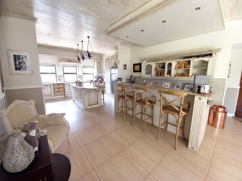 Spacious open-plan kitchen featuring a central island, breakfast bar with seating, custom cabinetry, and elegant timber ceiling finishes.