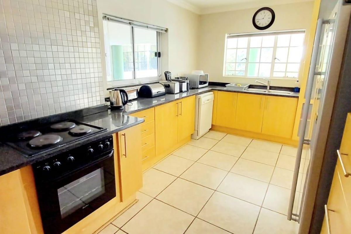 A functional kitchen featuring light wood cabinetry, granite countertops, a mosaic tile backsplash, built-in oven, and ceramic floor tiles.