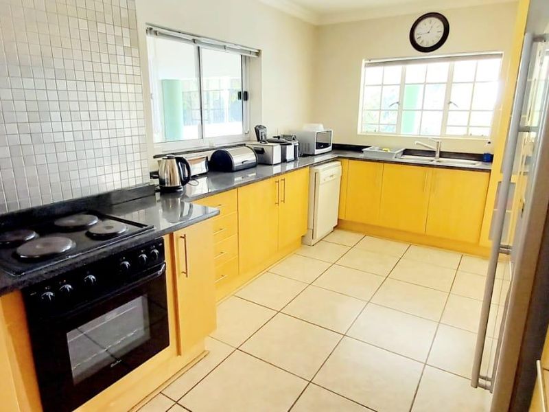 A functional kitchen featuring light wood cabinetry, granite countertops, a mosaic tile backsplash, built-in oven, and ceramic floor tiles.