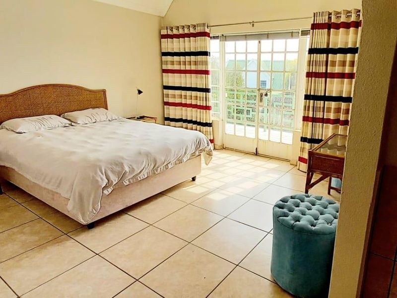 Spacious bedroom featuring tiled flooring, vaulted ceilings, and direct access to a balcony through classic French doors.
