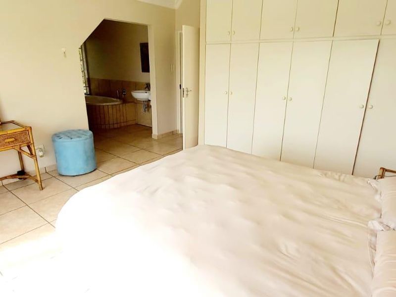 A bedroom featuring built-in cupboards, tiled flooring, and direct access to an en-suite bathroom.
