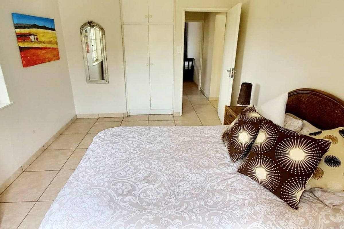 A bedroom featuring tiled flooring, built-in cupboards, and natural light from the window.