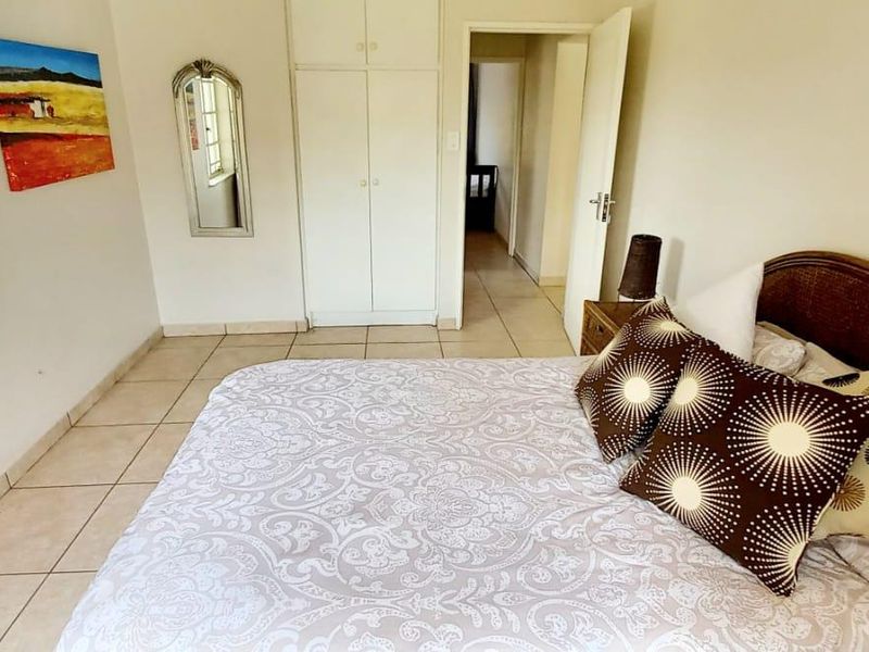 A bedroom featuring tiled flooring, built-in cupboards, and natural light from the window.
