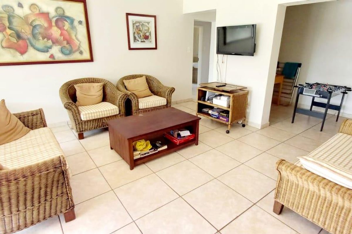 A living room area featuring neutral ceramic floor tiles and an open-plan layout leading to a staircase.