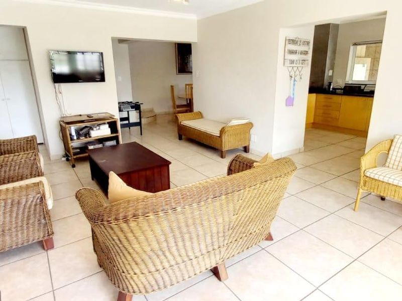 Open plan living area featuring tiled floors and a view into the adjacent kitchen with built-in cabinetry.