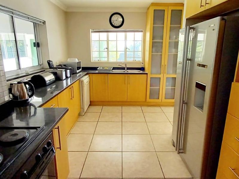 A functional kitchen featuring wooden cabinetry, granite countertops, tiled flooring, and a tiled backsplash, providing ample storage and workspace.