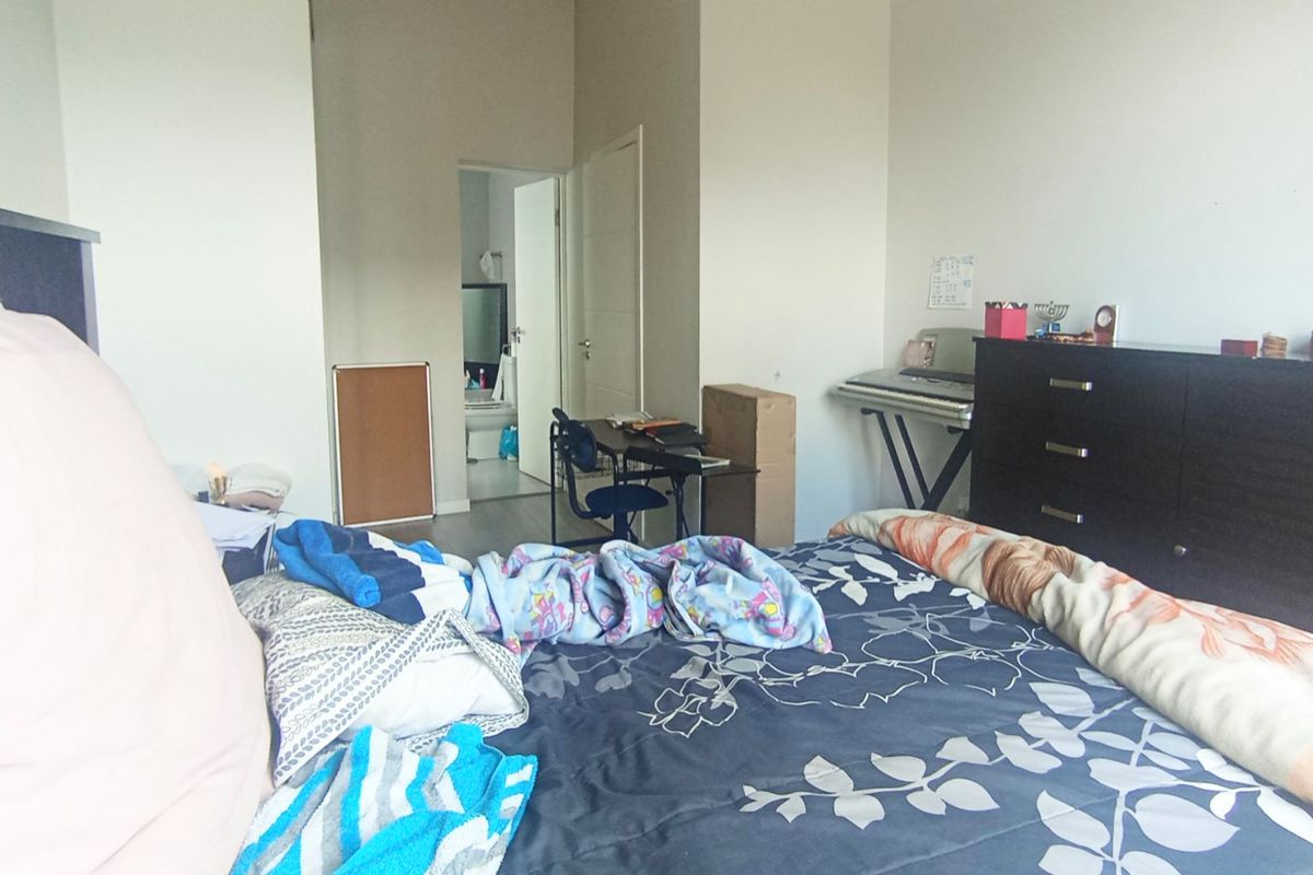 A bedroom featuring neutral walls and laminate flooring, with an adjoining en-suite bathroom visible through the doorway.