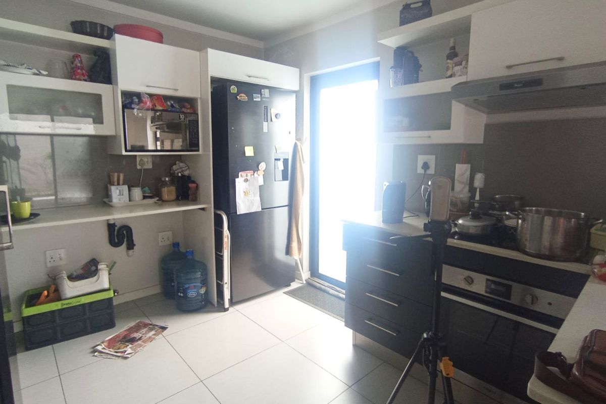 A functional kitchen featuring built-in cabinetry, a hob, an oven, and an extractor fan, with direct access to the exterior via a glass door.