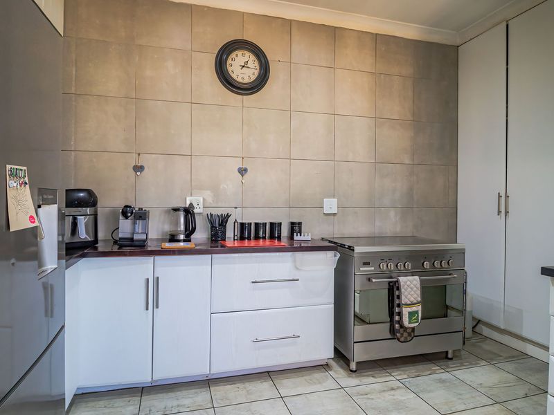 A functional kitchen featuring white cabinetry, tiled backsplash, and a stainless steel freestanding oven, providing a clean and practical workspace.