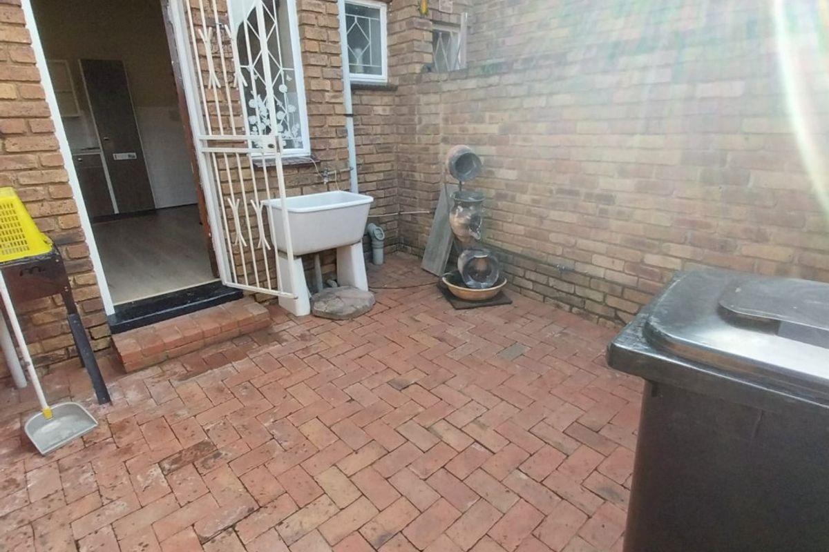 A private rear courtyard featuring brick paving, an external utility sink, and secure access to the interior living space.