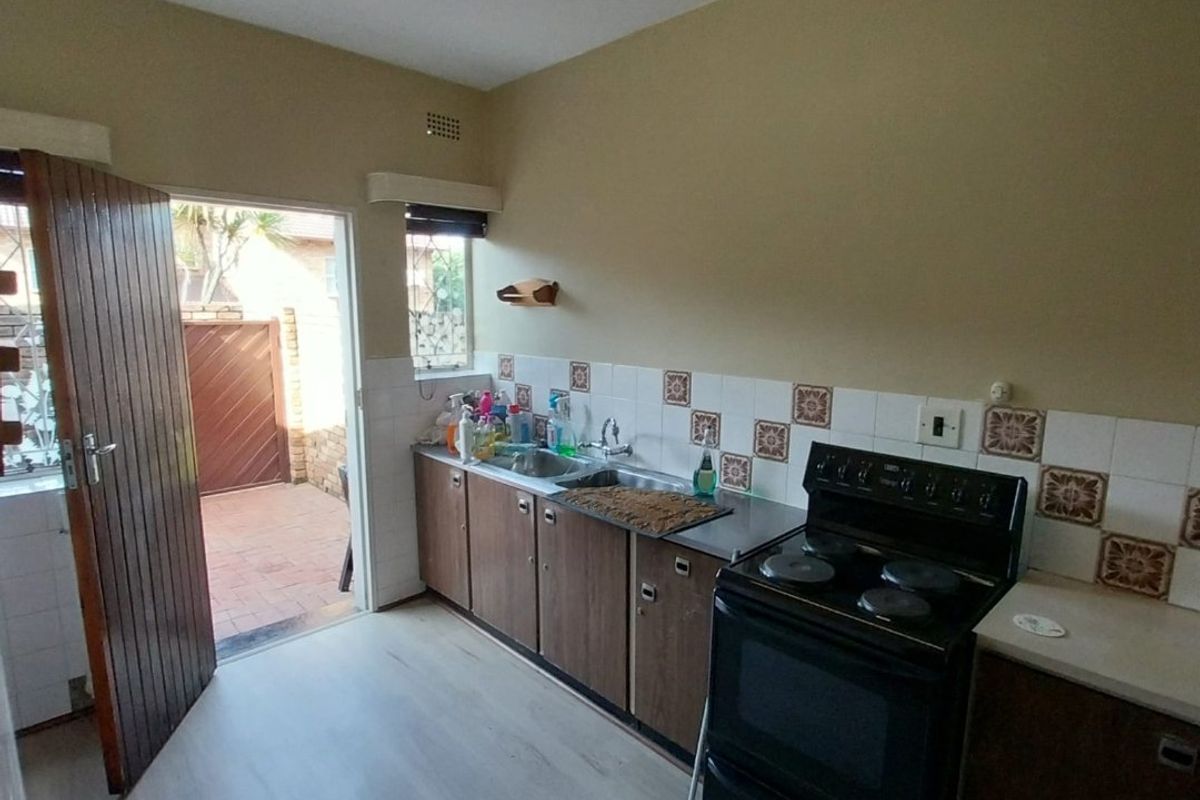 A functional kitchen featuring built-in cabinetry, a tiled backsplash, and a freestanding stove, with direct access to an outdoor patio area.