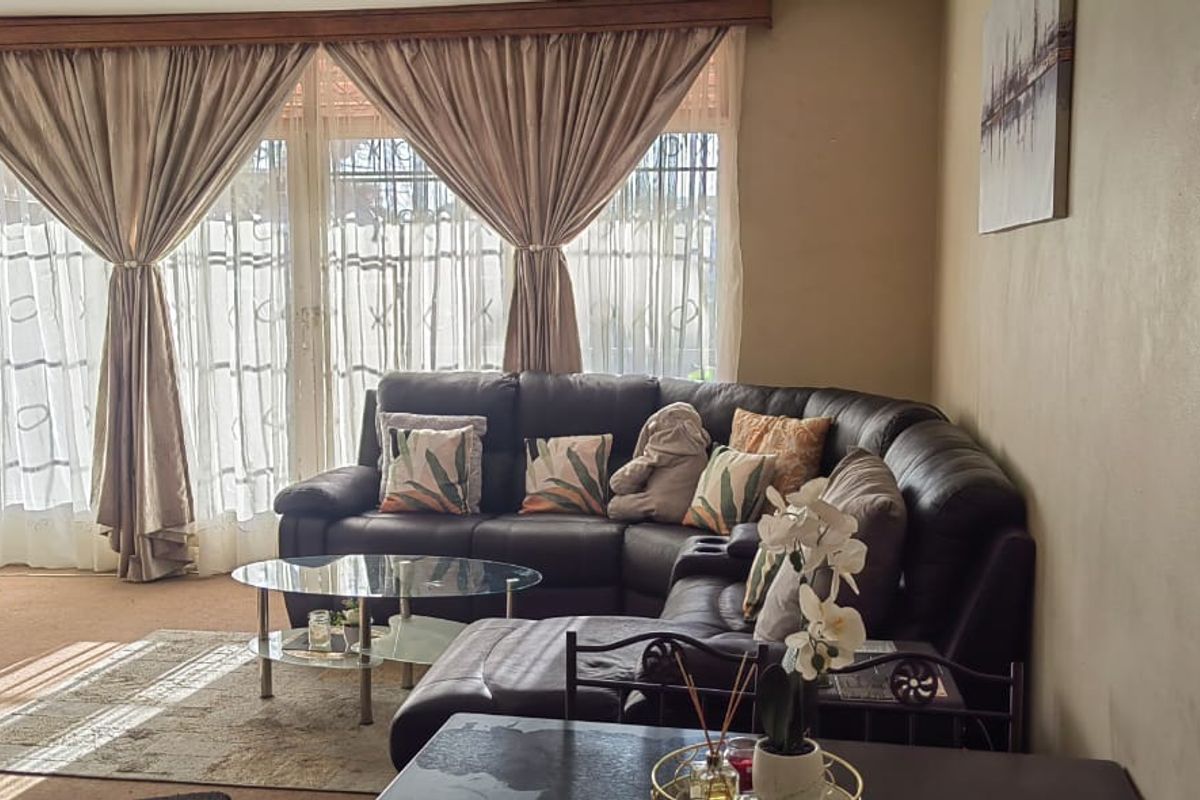 A living room featuring large sliding glass doors with curtains, providing natural light and access to the exterior.