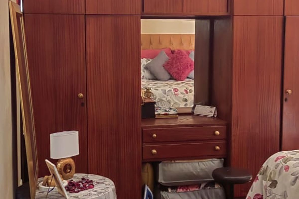Bedroom featuring extensive built-in wooden cabinetry with integrated vanity and mirror, providing ample storage space.