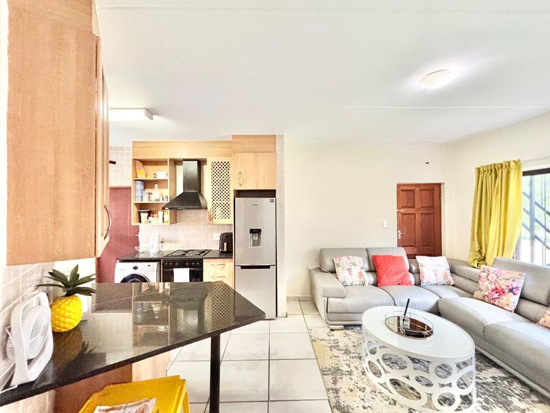 Open-plan living area featuring a functional kitchen with granite countertops, built-in cabinetry, and tiled flooring throughout the combined space.