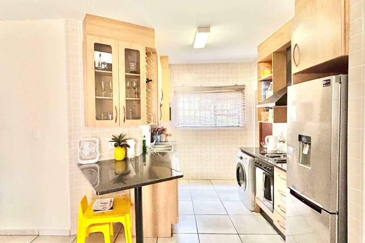 A functional kitchen featuring light wood cabinetry, granite countertops, tiled flooring, and a built-in oven with extractor fan.
