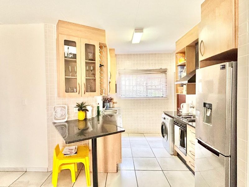A functional kitchen featuring light wood cabinetry, granite countertops, tiled flooring, and a built-in oven with extractor fan.