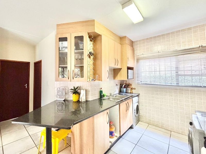 Functional kitchen featuring light wood cabinetry, granite countertops, tiled backsplash, and integrated laundry facilities, offering a practical layout for daily use.