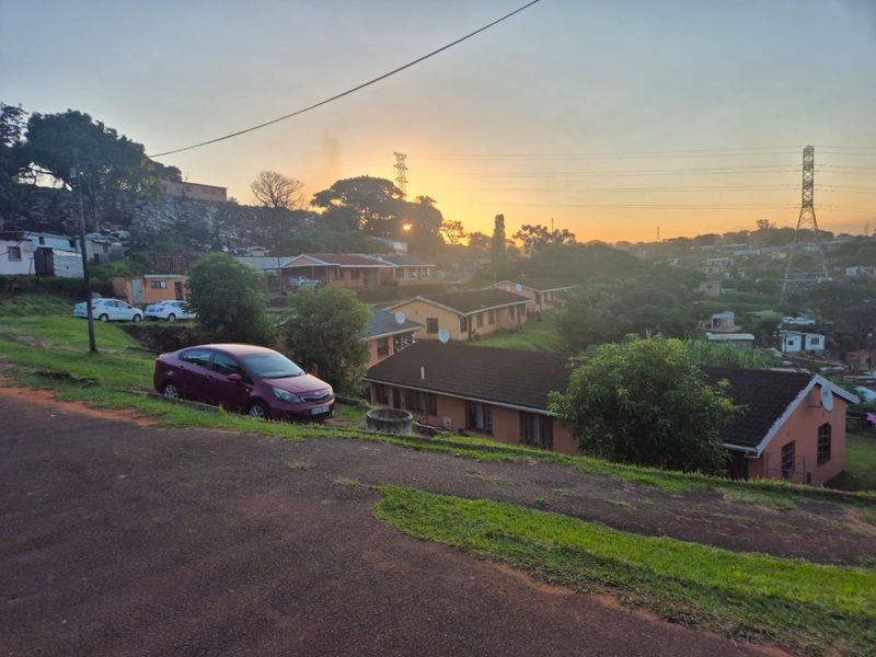 A street-level view of a residential neighborhood featuring multiple single-story homes with tiled roofs during sunset.