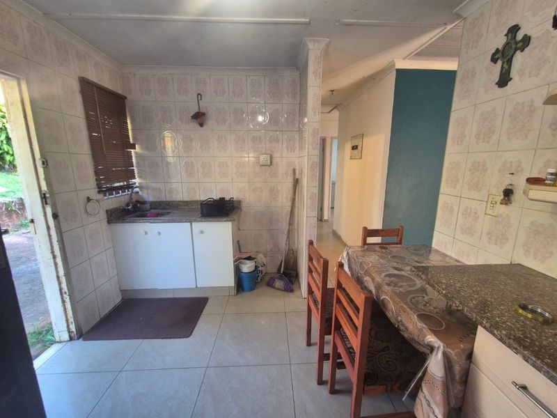 A functional kitchen area featuring tiled walls, built-in cabinetry with stone countertops, and direct access to an outdoor space.
