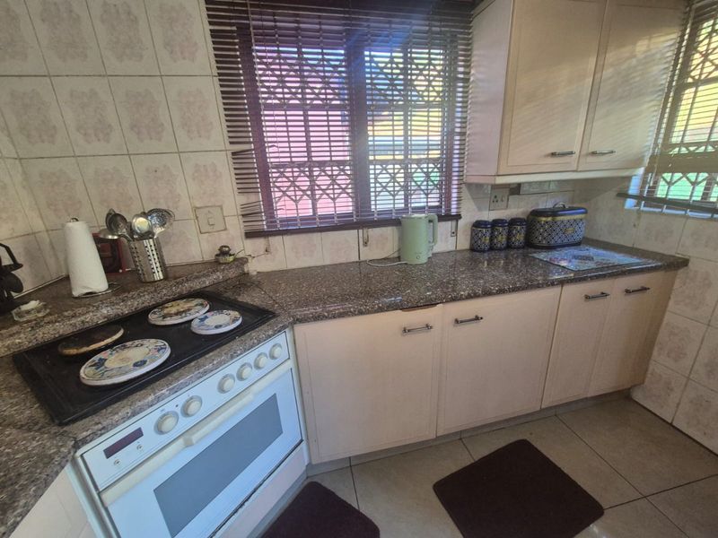 A functional kitchen featuring granite countertops, built-in cabinetry, a tiled backsplash, and a built-in stove, offering a practical layout for daily cooking.
