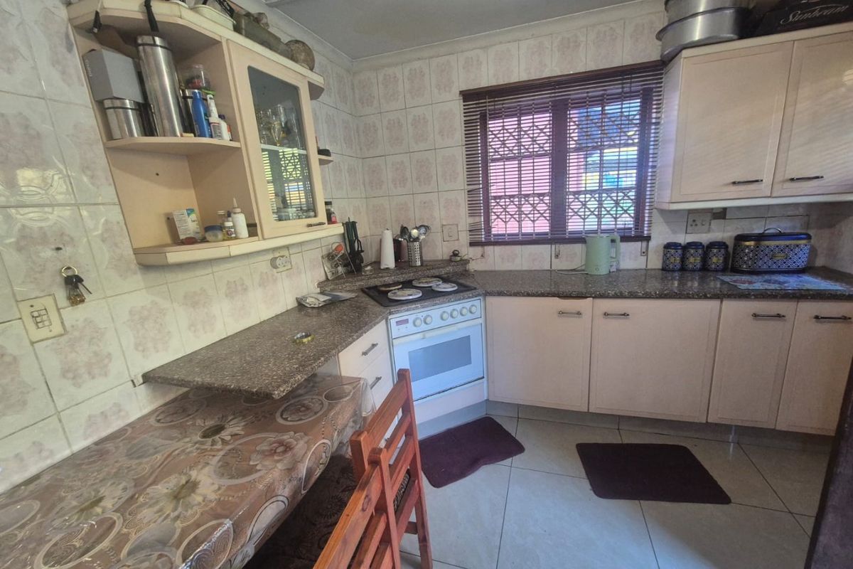 A functional kitchen featuring built-in cabinetry, granite countertops, a freestanding stove, and tiled finishes throughout, offering a practical layout for daily use.
