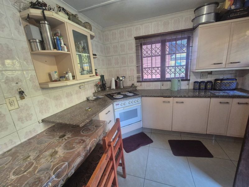 A functional kitchen featuring built-in cabinetry, granite countertops, a freestanding stove, and tiled finishes throughout, offering a practical layout for daily use.
