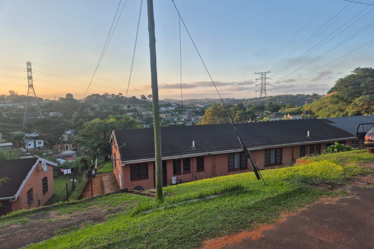 An elevated view of the rear exterior of the apartment building, featuring a tiled roof and brick facade overlooking the surrounding neighborhood.
