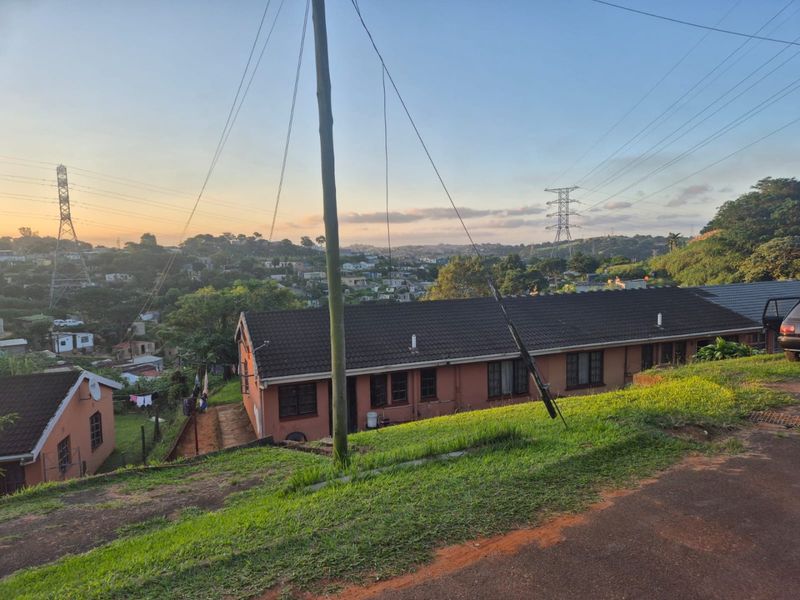 An elevated view of the rear exterior of the apartment building, featuring a tiled roof and brick facade overlooking the surrounding neighborhood.