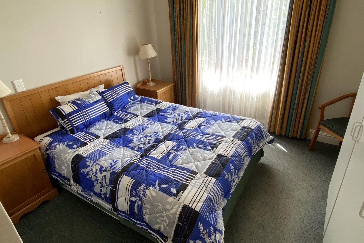 A standard bedroom featuring carpeted flooring and large window with curtain tracks, offering a functional space ready for modern updates.