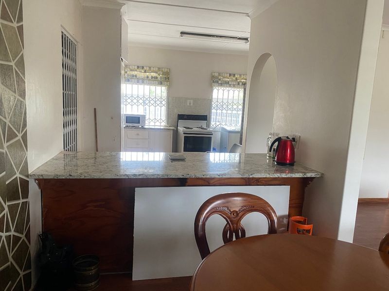 Open plan kitchen area featuring a granite breakfast bar, freestanding stove, and security gates, connecting to the adjacent living space.