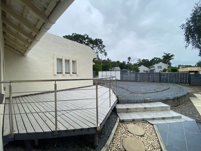 Outdoor entertainment area featuring a raised timber deck with stainless steel balustrades, adjacent paved patio, and stone garden steps.
