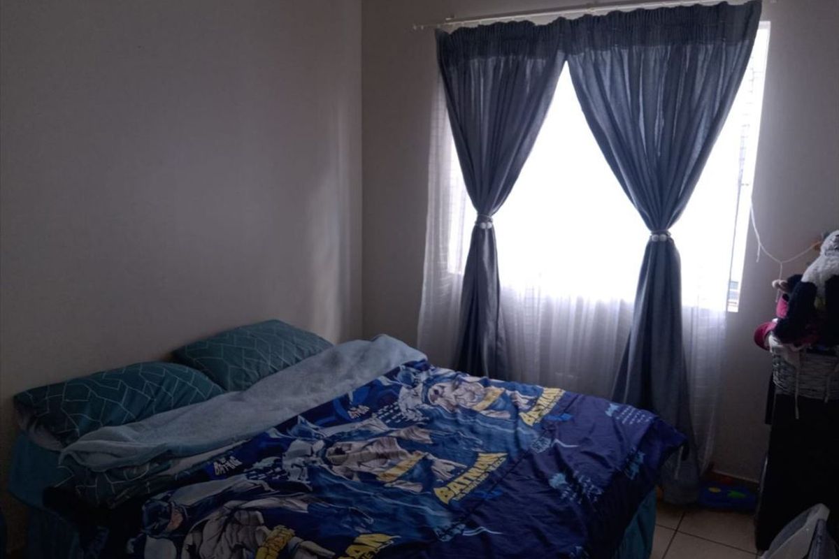 A standard bedroom featuring tiled flooring and a window with installed curtain rods.