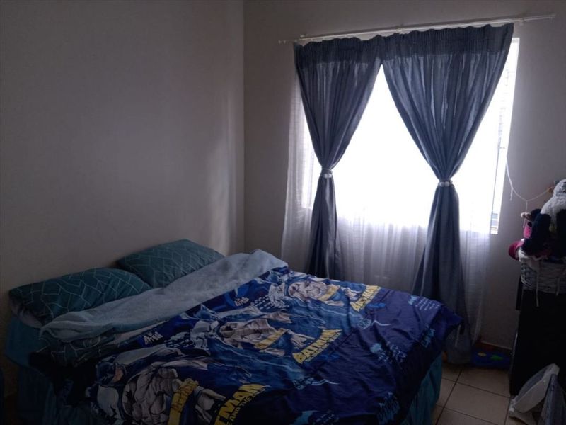 A standard bedroom featuring tiled flooring and a window with installed curtain rods.