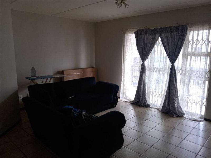 A living room featuring tiled flooring and a sliding door with an integrated security gate, providing access to the exterior.